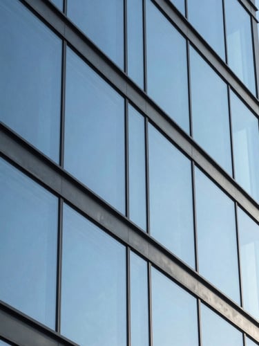 Extreme close-up architectural angle of pristine structural glass facade reflecting a bright, clear blue sky with zero residue, highlighting sharp geometric lines and absolute optical clarity.