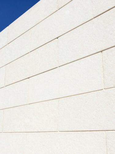 Close-up macro shot of clean, light-colored stone masonry with precise, newly sealed grout lines under high-key commercial lighting