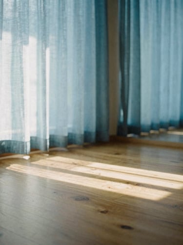 A quiet, sunlit yoga studio with natural wood floors and soft blue linen curtains, diffused morning light casting long shadows, serene film photography.