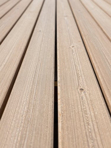 Sharp, straight-on architectural close-up of perfectly aligned timber decking joints, bright natural daylight, clean lines, professional carpentry craftsmanship.