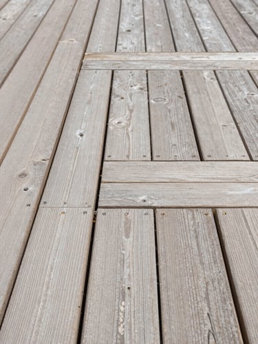 Straight-on architectural shot of perfectly aligned timber decking joints under bright natural daylight, highlighting millimeter-precise craftsmanship and clean structural lines.