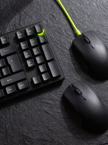 Overhead flat-lay of a sleek modern desk setup on a dark slate background, featuring a mechanical keyboard, a matte black mouse, and neon green cable accents, crisp studio lighting, high contrast shadows