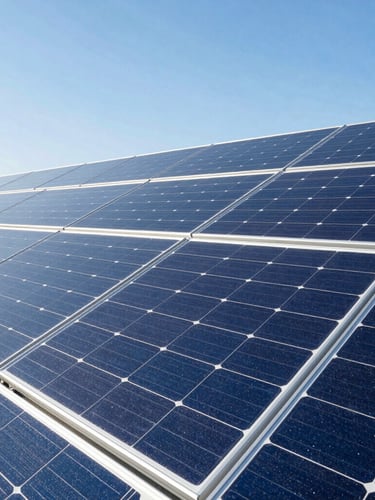 Close-up of high-tech monocrystalline solar panels reflecting a bright blue sky, sharp industrial lines, premium architectural daylight.