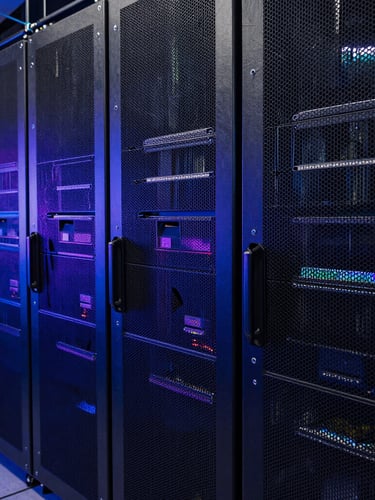 Ultra-wide macro photograph of high-density server rack arrays, moody deep blue and violet directional edge lighting, dark metallic textures, absolute precision.