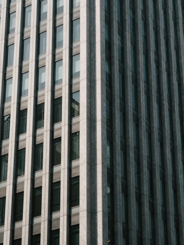 Abstract architectural pattern of a modern corporate skyscraper facade, high-contrast shadows, cool desaturated tones, 35mm