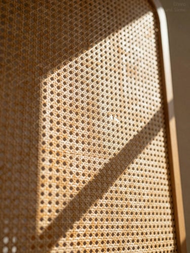 Macro texture shot of woven rattan screen casting geometric shadows in a sunlit architectural space, low-angle warm afternoon light, 35mm lens