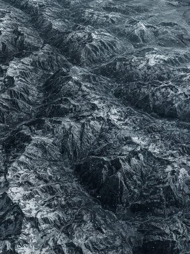 Wide panoramic desaturated high-altitude satellite topography of the Rocky Mountains, showing subtle wireframe overlays and data points, cold high-contrast laboratory light, extreme overhead perspective.