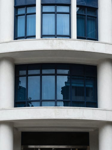 Architectural detail of a grand cooperative bank building in Maharashtra, structured concrete pillars, cool window daylight, deep navy tones, sharp focus.