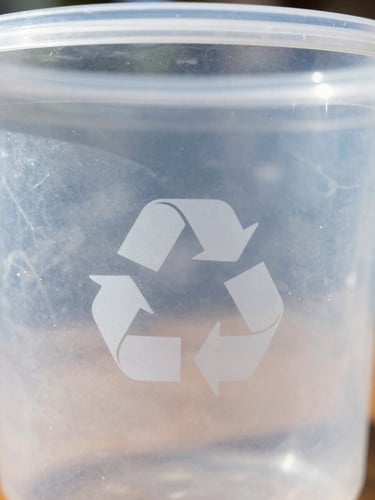 A close-up of a clean plastic container showing a clear recycling symbol with a number inside, bright natural daylight, 35mm lens.