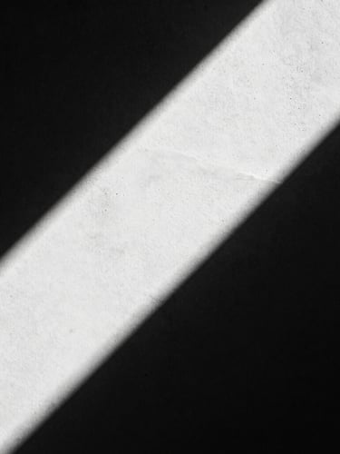 Extreme close-up of high-contrast architectural concrete shadows, hard directional studio light, deep black and white tones, 35mm film grain