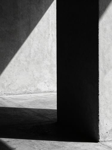 Extreme close-up of high-contrast architectural shadows on raw concrete, hard directional light, deep shadows, desaturated black and white, 35mm film grain