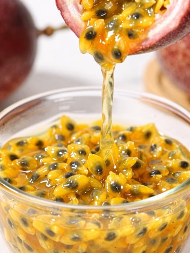 Close-up of vibrant yellow passion fruit pulp being poured into a clean glass container, bright natural daylight, sharp focus on the glossy texture, professional food styling.