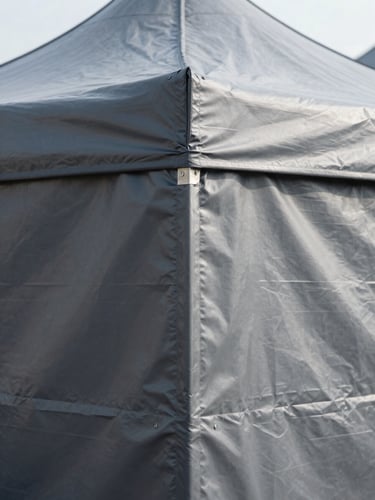 Close-up of heavy-duty double-stitch seams on a dark grey PVC tarpaulin tent, bright natural daylight, industrial commercial photography