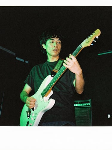 Low-angle gritty concert photography of a guitarist performing under high-contrast neon acid-green stage lighting, dark atmospheric background, 35mm flash style