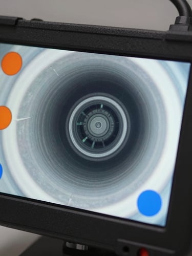 Close-up macro shot of a modern high-definition video inspection screen displaying a clean pipe interior, sharp contrast orange and blue indicators, professional plumbing diagnostic equipment.