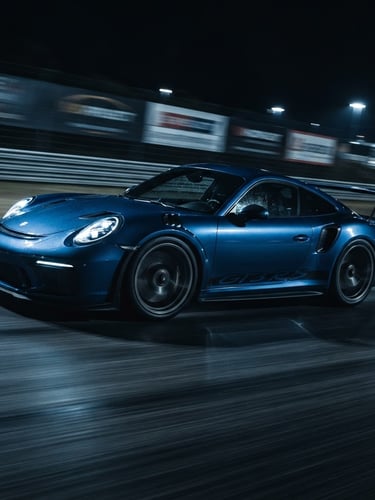 Low-angle dynamic shot of a modern sports car with motion blur on a dark track, dramatic blue studio rim lighting, cool dark tones, sharp detail, 50mm lens