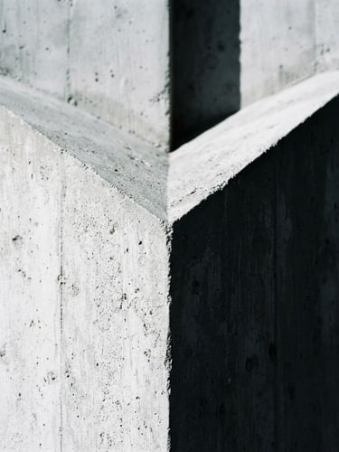 Extreme close-up of a sharp architectural concrete corner, dramatic natural light casting deep geometric shadows, 35mm lens, high-contrast cool tones.