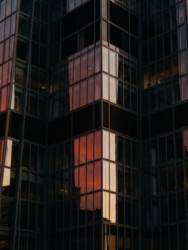 Close-up architectural crop of a UK skyscraper reflecting soft golden hour light on its glass facade, editorial 35mm composition with deep shadows