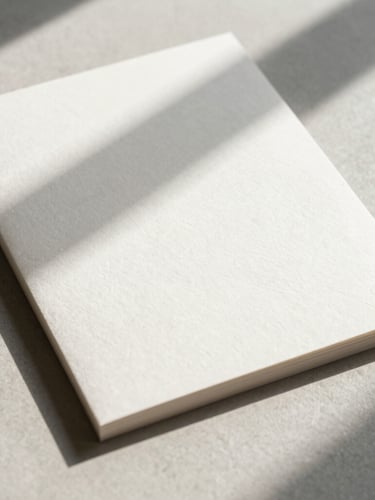 Strict 90-degree flat-lay of embossed heavy paper stationery, deep tactile textures, soft diffused daylight casting long gentle shadows.