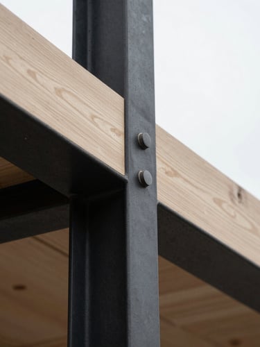 Extreme close-up of an architectural joint where blackened steel meets raw white oak, soft overcast daylight, sharp focus on material transition.