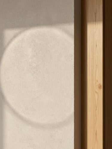 Soft natural daylight casting a subtle circular shadow on a textured microcement wall, intersecting with a flawless, sharp light oak joinery corner. Minimalist, architectural, serene composition with generous negative space, high-end detail.
