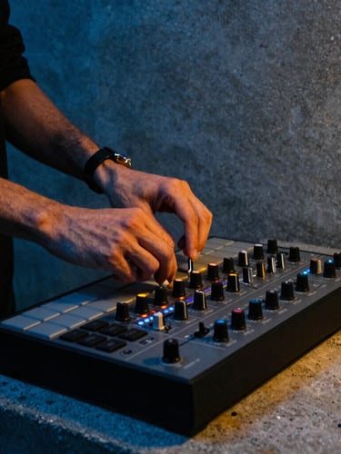 Low-angle portrait of a producer's hands adjusting knobs on a classic MPC sampler, dramatic midnight blue and warm amber neon lighting, raw concrete background