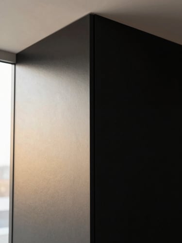 Close-up of a perfectly smooth, freshly painted wall corner in a modern Belgian interior, with light catching the flawless surface, geometric framing, high-contrast black and gold tones, editorial style.