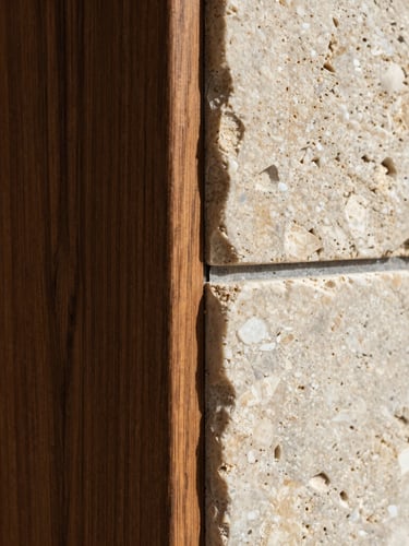 Extreme close-up of a perfectly executed architectural joint, dark oak wood panel meeting raw travertine stone under crisp natural light