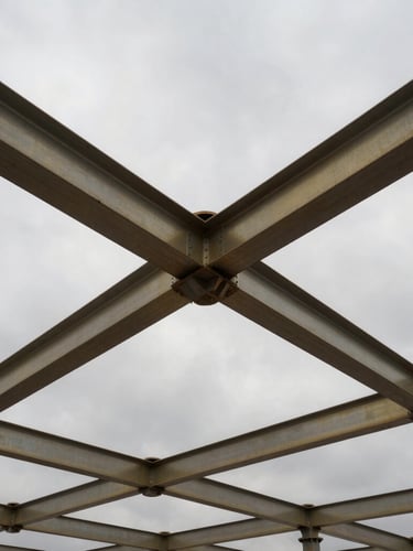Low-angle heroic shot of a heavy infrastructure construction site with steel beams under dramatic overcast skies, desaturated steel tones