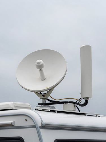 Close overhead shot of Starlink dish and LTE antenna mounted side by side on an RV rooftop, cables neatly routed, overcast daylight, no glare, hardware clearly identifiable