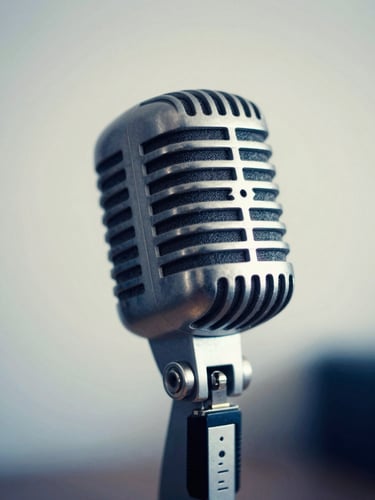 An elegant close-up of a vintage studio microphone, soft warm studio lighting, deep blue tones, shallow depth of field, 35mm editorial photography