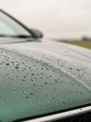 Macro shot of water beading perfectly on deep green metallic car paint, soft overcast Irish daylight, shallow depth of field