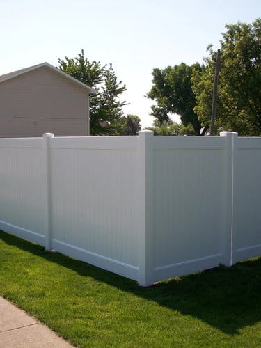 A clean white vinyl privacy fence with a matching gate installed in a residential backyard.