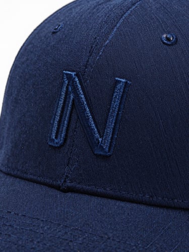 Macro close-up of high-definition embroidery on a premium navy blue corporate cap, bright studio lighting, clean white background, sharp focus