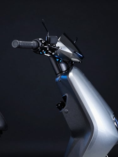 Crisp industrial photography of a sleek electric moped profile in a dark studio, metallic silver frame, cool high-contrast blue highlights, 50mm lens
