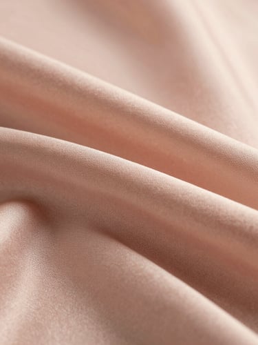 Macro close-up shot of sand-washed blush pink silk fabric, showing the fine matte texture and delicate weave, soft golden-hour light highlighting the folds.