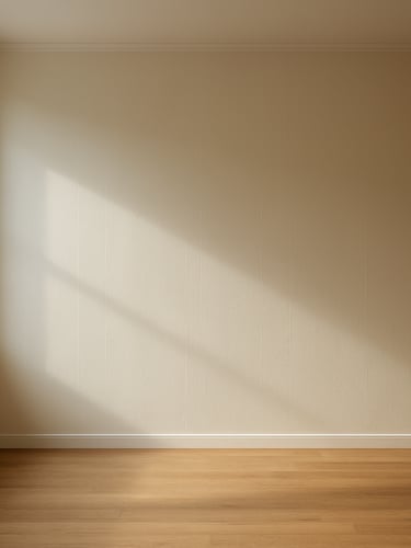 Wide room shot of a freshly painted living room wall in warm off-white, natural daylight streaming through a window to the left, clean roller lines visible on the smooth surface, no furniture, empty floor