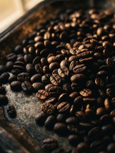 Moody low-key macro shot of dark roasted coffee beans resting on an antique silver tray, dramatic chiaroscuro lighting, warm golden-hour window light, 35mm film.
