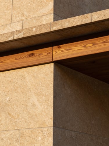 Close-up of architectural details showing warm laterite stone and teak wood finishes under golden hour light