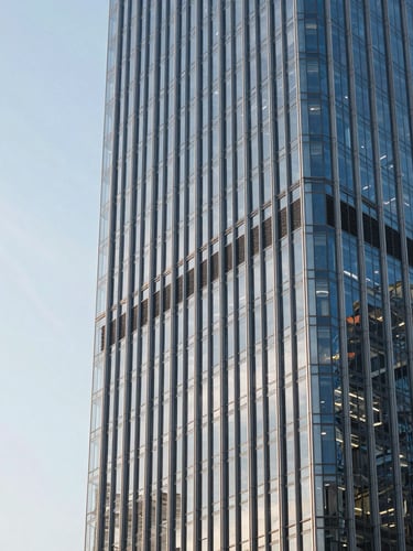 Wide panoramic 21:9 framing of a glass and steel skyscraper facade in a global financial hub, sharp architectural lines reflecting crisp cool-toned daylight, extreme close-up on structural geometry with generous negative space on the left.