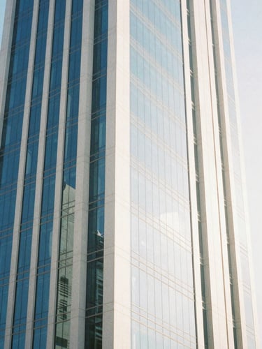 An elegant architectural detail of a modern glass skyscraper in Riyadh reflecting bright morning daylight, clean minimalist lines, negative space, 35mm