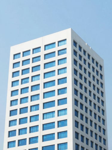 Bright editorial architectural detail of a modern high-rise office building in Mumbai, clear blue sky, soft natural daylight, clean white and royal blue tones, 35mm.