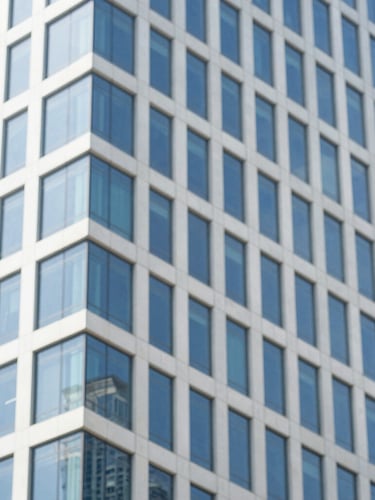 Close-up architectural detail of a modern glass skyscraper in Mumbai reflecting bright daylight, clean lines, minimalist editorial style, 35mm.