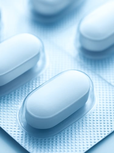 Macro focus on pharmaceutical tablet strips in a sterile blister pack, clinical white light with soft blue highlights, high-compliance manufacturing, 50mm