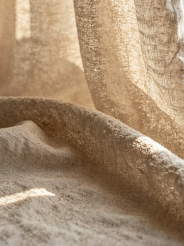 Close-up of premium linen fabric texture, soft natural golden hour window light, warm sand tones