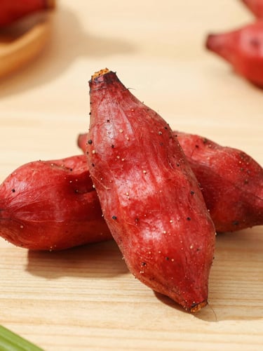 Bright editorial food photography of vibrant red scotch bonnets and textured yams on a clean wooden table, warm daylight, shallow depth of field, 50mm