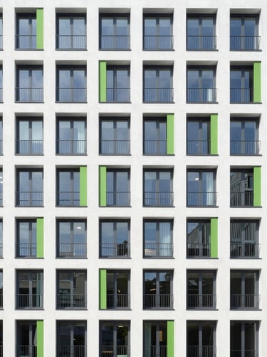 Wide architectural photograph of a modern multi-family apartment building in Frankfurt, clean modern facade, bright daylight, sharp focus, 35mm