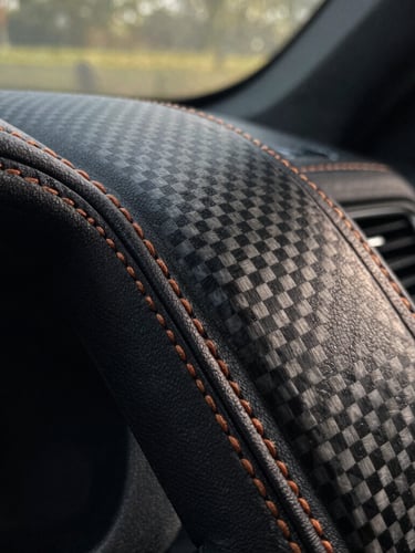 Extreme macro shot of hand-stitched leather and carbon fiber detailing inside a bespoke cabin, natural low-key lighting.