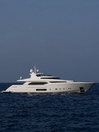 Wide-angle cinematic shot of a sleek 80-meter custom superyacht cruising through deep indigo water at dusk, low-key natural light highlighting the sharp architectural lines of the hull, minimalist composition with ample negative space.