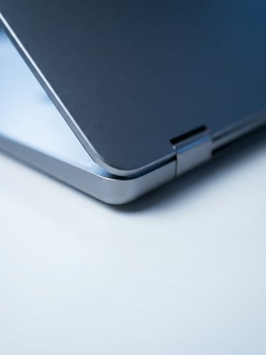 Sleek metallic laptop on a minimalist white desk, cool studio lighting with soft blue ambient fills, macro focus, 85mm